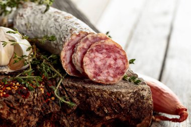 Geleneksel kuru sosis kekik, sarımsak, soğan ve baharatlı. Eski ahşap bir masada kurutulmuş sosis..