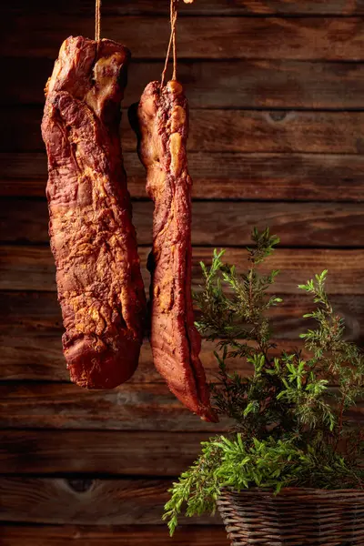 Homemade smoked pork ribs with juniper branches on the background of the old wooden wall.