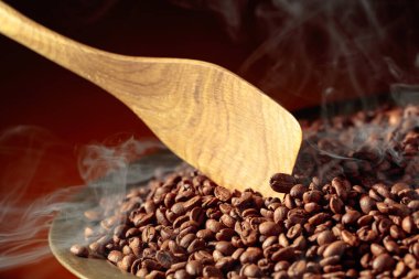 Orta pişmiş kahve çekirdekleri kızartma tavasında dumanlıdır. Boşluğu kopyala.