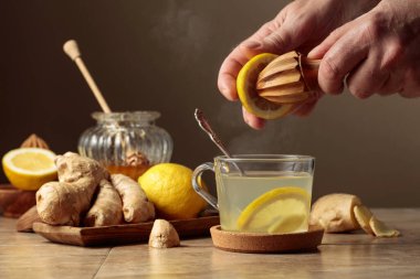 Kahverengi seramik masada limonlu ve ballı zencefil çayı. Meyve suyu eski bir meyve sıkacağıyla limondan sıkılır..