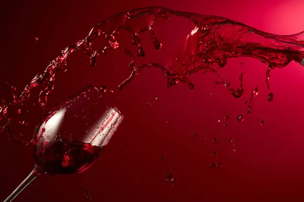 ガラスと赤ワインは濃い赤い背景に飛びつきます コピースペース — ストック写真