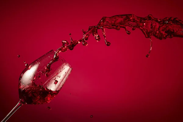 グラスと赤ワインは赤い背景に飛びつきます コピースペース — ストック写真