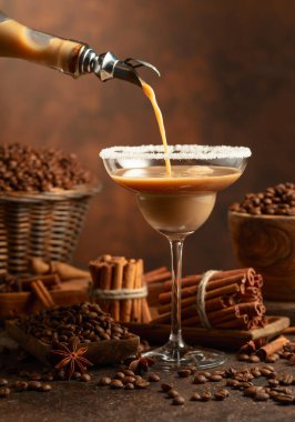 Çikolatalı martini kokteyli ya da İrlanda kremalı likörü şişeden bardağa doldurulur. Kahve çekirdekleri, tarçın çubukları ve anason masaya saçılmış..