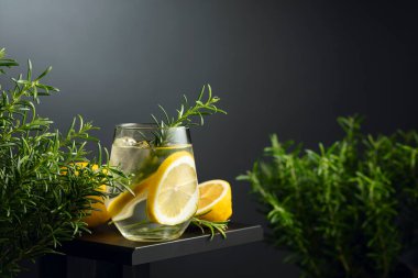 Buzlu, limonlu ve biberiyeli cin tonik. Karanlık bir arka planda canlandırıcı içecek. Boşluğu kopyala.