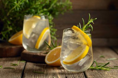 Eski ahşap bir masada buzlu, limonlu ve biberiyeli cin tonik. Boşluğu kopyala.