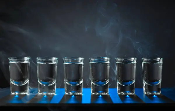 Αλκοολούχα Σφηνάκια Βότκας Δυνατό Ποτό Μικρά Ποτήρια Μαύρο Φόντο Μπλε — Φωτογραφία Αρχείου