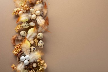 Paskalya kompozisyonu olarak bıldırcın yumurtaları, tüyler ve kurumuş çiçekler. Üst görünüm.