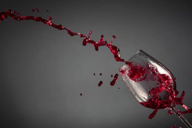 Koyu bir arka planda cam ve kırmızı şarap sıçraması. Boşluğu kopyala.