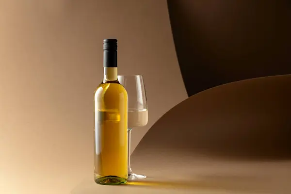米色背景下的白葡萄酒瓶和杯子 — 图库照片