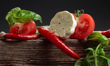 Baharatlı domates sosu yapmak için gerekli malzemeler. Eski ahşap bir masada taze domates, kırmızı biber, sarımsak ve fesleğen. Boşluğu kopyala.