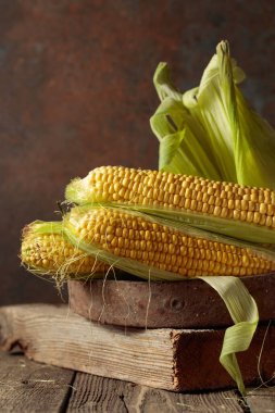 Fresh corn on cobs on a rustic wooden table.