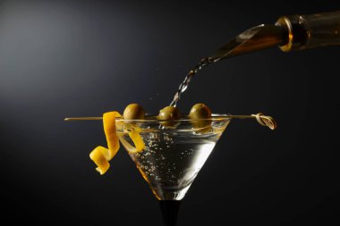 Siyah arka planda yeşil zeytinli ve limon kabuklu klasik sek martini kokteyli. Metnin için boş yer.