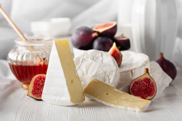 卡门贝尔奶酪 上面有无花果和蜂蜜 放在白色的木制桌子上 — 图库照片