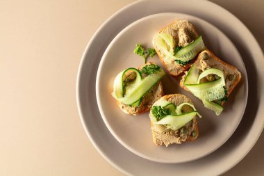 Pate, taze salatalık, kapari ve maydanozlu sandviç. Bej arka planda ezmeli tost. Üst görünüm, alanı kopyala.