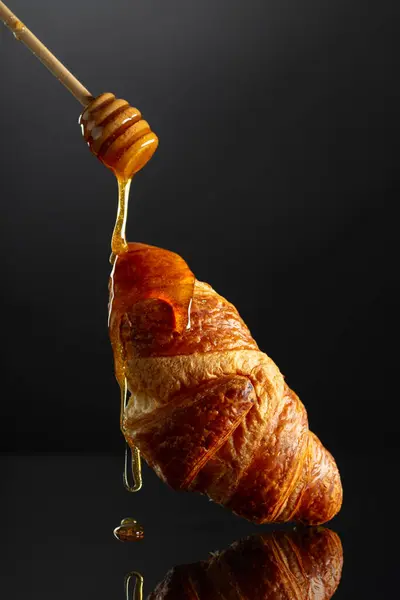 Verse Gebakken Croissant Met Honing Een Zwarte Reflecterende Achtergrond — Stockfoto