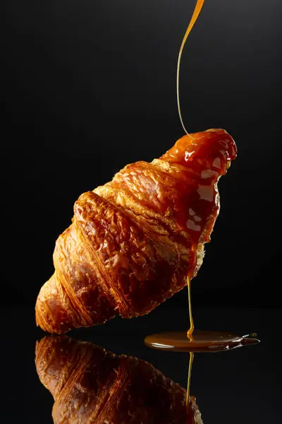 Verse Gebakken Croissant Met Karamelsaus Een Zwarte Reflecterende Achtergrond — Stockfoto