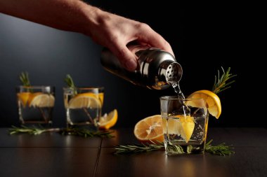 Limonlu ve biberiyeli kokteyl Cin ve Tonik. Barmen bardaktan bardağa kokteyl doldurur..