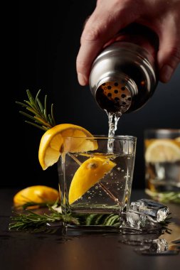 Limonlu ve biberiyeli kokteyl Cin ve Tonik. Barmen bardaktan bardağa kokteyl doldurur..