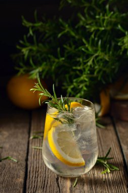 Eski ahşap bir masada buzlu, limonlu ve biberiyeli cin tonik. Boşluğu kopyala.