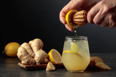 Ginger Ale with ice and lemon. Juice is squeezed out of a lemon with an old wooden juicer. clipart