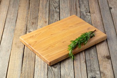 Tahta kesme tahtası ve biberiye eski ahşap bir masada. Mutfak geçmişi. Boş tahta kesme tahtası, ürün görüntüleme alanı.