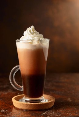Eski kahverengi bir masada cam bardakta krem şantili sıcak çikolata. Boşluğu kopyala.