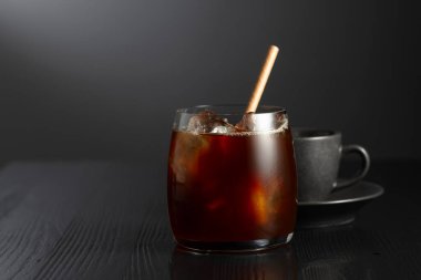 Siyah ahşap bir masada buzlu kahve ve bir fincan sade kahve. Boşluğu kopyala.