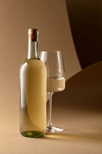 米色背景下的白葡萄酒瓶和杯子 — 图库照片