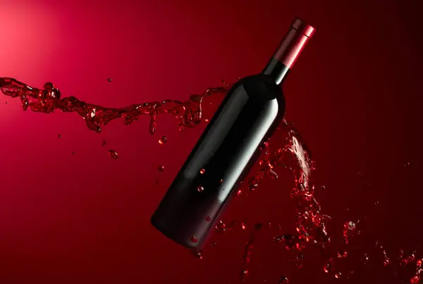 ボトルと赤ワインは濃い赤い背景に飛びつきます コピースペース — ストック写真