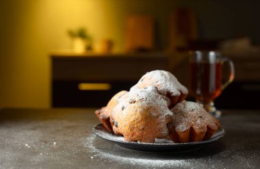 Ev yapımı kuru üzümlü kekler üzerine pudra şekeri serpiştirilmiş. Kahvaltı mutfak masasında..