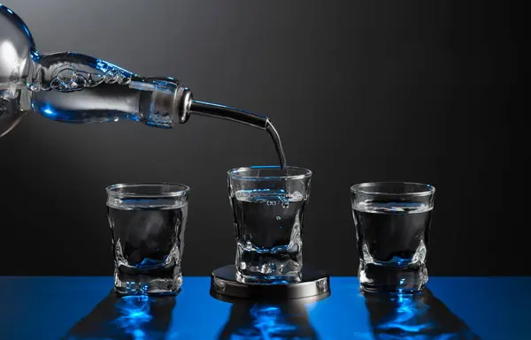 Vodka Pouring Bottle Glass Dark Background Blue Backlight Copy Space — Stock Photo, Image