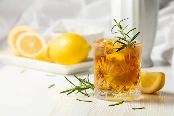 冰茶或含冰的酒精鸡尾酒 迷迭香和柠檬片放在白桌上 新鲜健康的冷柠檬饮料 冰茶和柠檬茶 — 图库照片