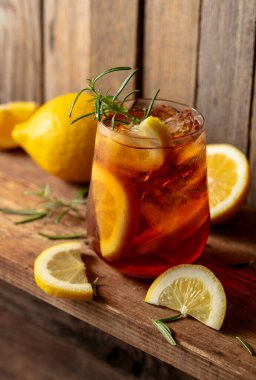 Buzlu çay ya da eski ahşap bir masada buzlu, biberiyeli ve limon dilimli alkollü kokteyl. Taze, sağlıklı, soğuk limon suyu. Buzlu ve limonlu çay..