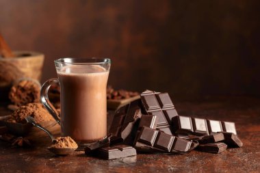 Kahverengi bir şarap masasında acı çikolata ve bir bardak kakao. Boşluğu kopyala.