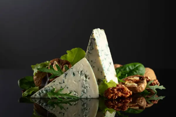 蓝色奶酪 有核桃和新鲜蔬菜 背景是黑色的 图库照片
