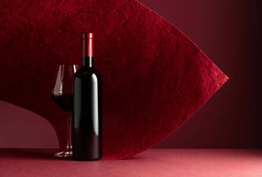 Kırmızı arka planda bir şişe kırmızı şarap. Metnin için boşluk kopyala.