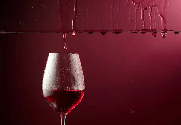 红酒流入杯子里 带有复制空间的深红色背景 图库图片
