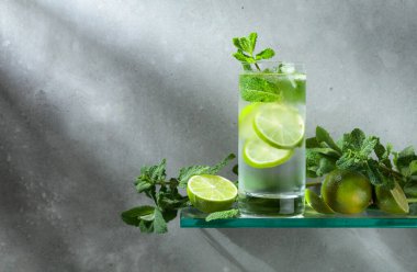 Buzlu, limonlu ve naneli mojito. Gri arka planda sisli bardakta buzlu içecek. Boşluğu kopyala. 