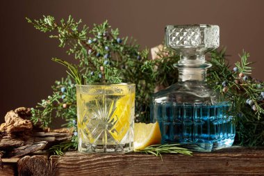 Buzlu, limonlu ve biberiyeli buzlu cin tonik kokteyl. Ardıç dallarıyla ferahlatıcı bir içecek ve eski bir kalas üzerinde kapanlar.. 