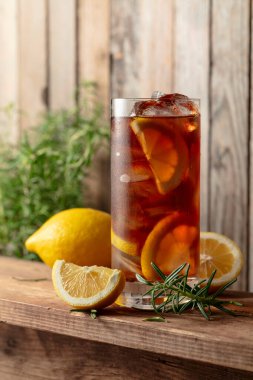 Buzlu çay ya da eski ahşap bir masada buzlu, biberiyeli ve limon dilimli alkollü kokteyl. Taze, sağlıklı, soğuk limon suyu. Buzlu ve limonlu çay..