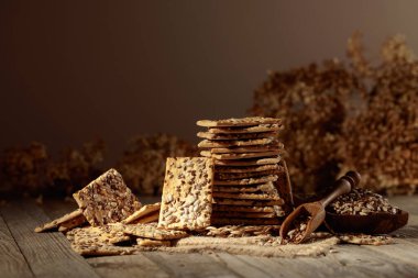 Eski ahşap bir masada ayçiçeği ve keten tohumlu çıtır krakerler. Basit sağlıklı yiyecekler. Boşluğu kopyala.