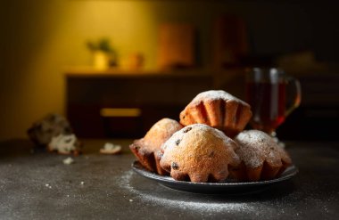 Ev yapımı kuru üzümlü kekler üzerine pudra şekeri serpiştirilmiş. Kahvaltı mutfak masasında..