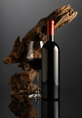 Siyah yansıtıcı arka planda bir şişe kırmızı şarap. Arka planda eski yıpranmış bir pürüz var. Metnin için alanı olan ön görünüm.