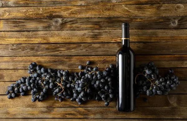 古い木のテーブルに赤ワインのブルーブドウとボトル コピースペース ストックフォト