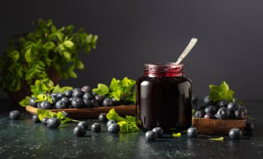 Yaban mersini reçeli ve koyu mavi arka planda yaprakları olan taze böğürtlen. Boşluğu kopyala.