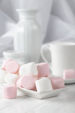 Mutfak aletleriyle ahşap bir masada pembe ve beyaz şekerlemeler..