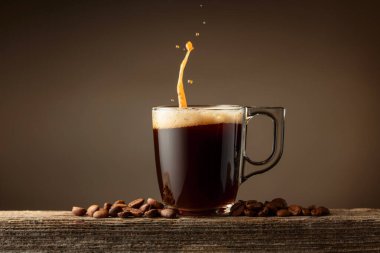 Kahverengi arkaplanlı espresso bardağı. Kahve fincanı ve kavrulmuş kahve çekirdekleri eski bir tahtanın üzerinde..