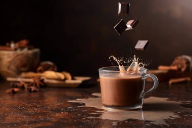 Koyu çikolata parçaları bir bardak kakao içeceğinin içine düşer ve güzel bir su sıçratır. Boşluğu kopyala.