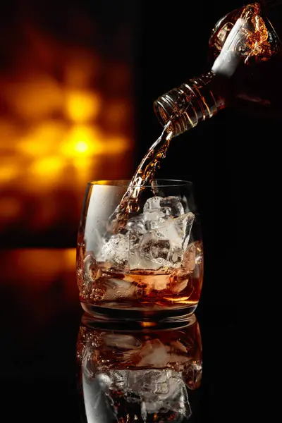 Whisky Uit Een Fles Een Glas Met Ijs Gieten Rechtenvrije Stockafbeeldingen