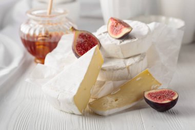 Beyaz ahşap bir masada incirli ve ballı peynirli Camembert peyniri..